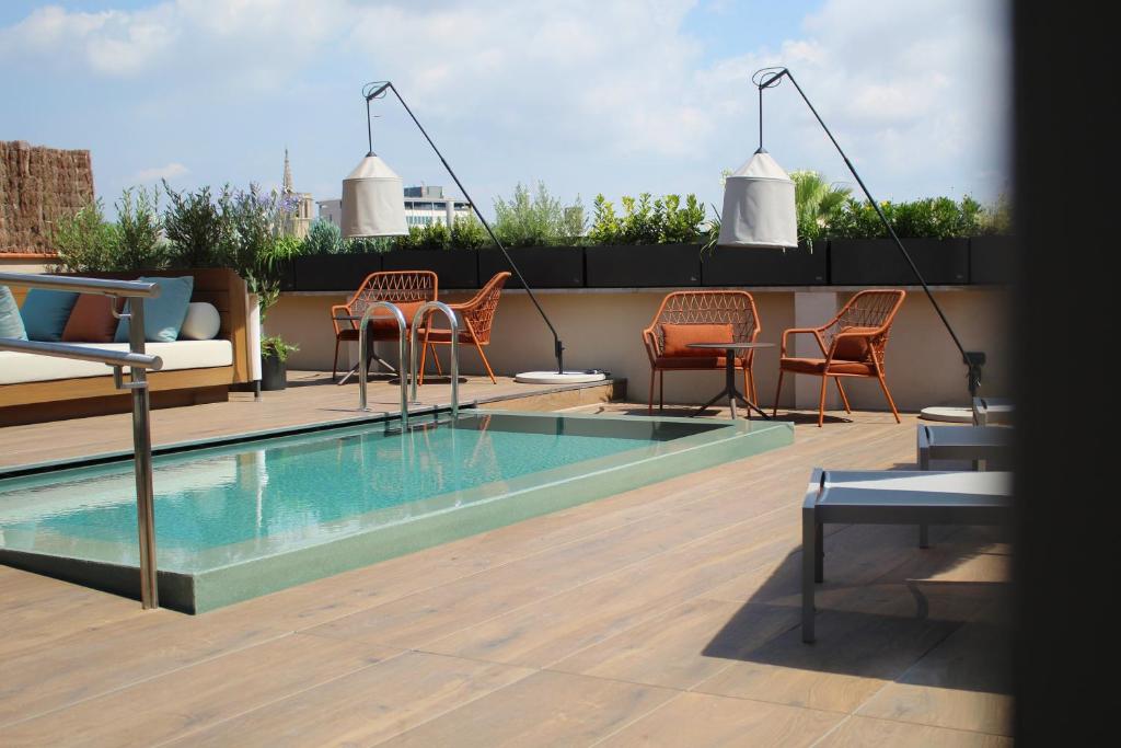 eine Terrasse mit Stühlen und einem Swimmingpool auf einem Dach in der Unterkunft Hotel Medinaceli 4 Sup in Barcelona