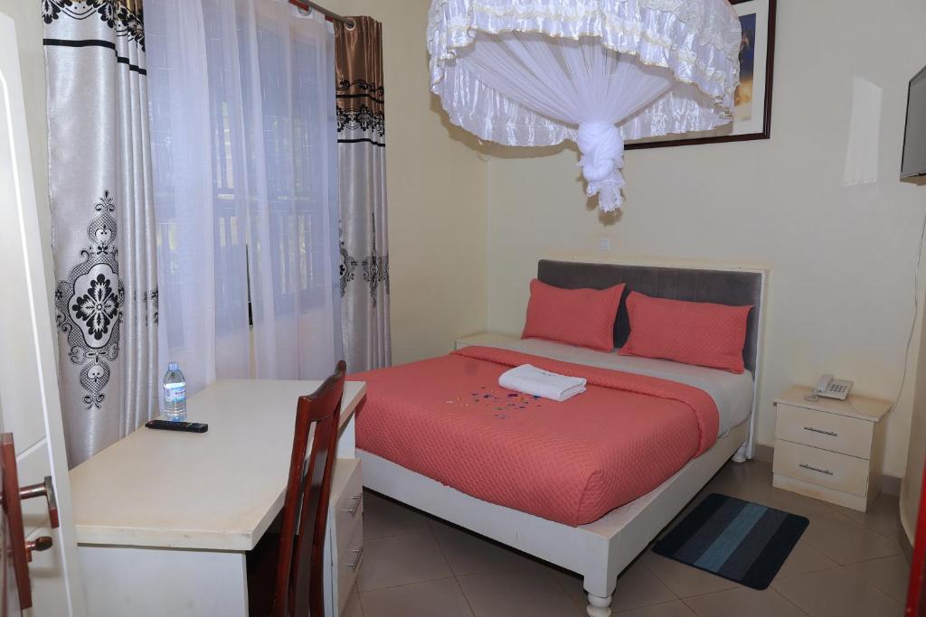 a small bedroom with a bed and a table at Bavah Airport Hotel in Entebbe