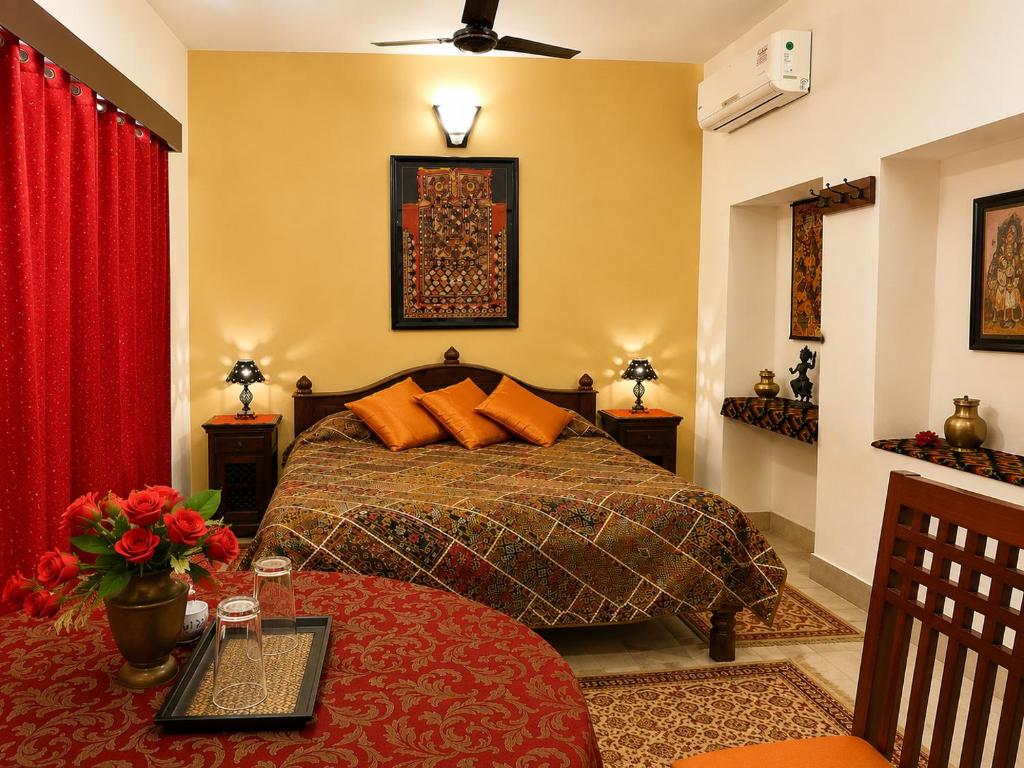 a bedroom with a bed with orange pillows and a table at Killa Bhawan Lodge in Jaisalmer