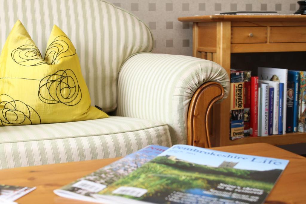 a living room with a chair and a table with a book at Ty Llwyd in Treffynnon 