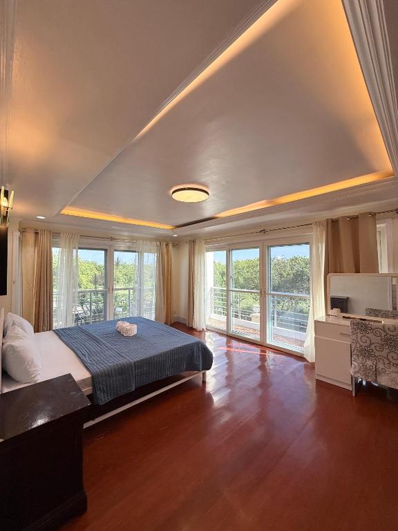 a bedroom with a large bed and windows at Dolores Cabin & Breakfast in Mactan