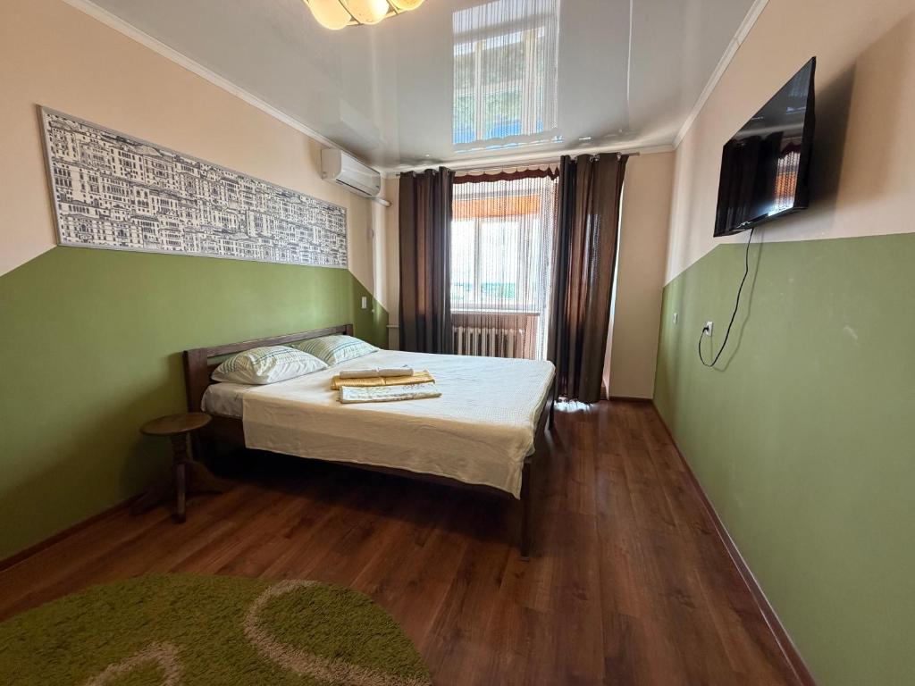 a small bedroom with a bed and a television at Соборная Апартаменты in Kamianets-Podilskyi