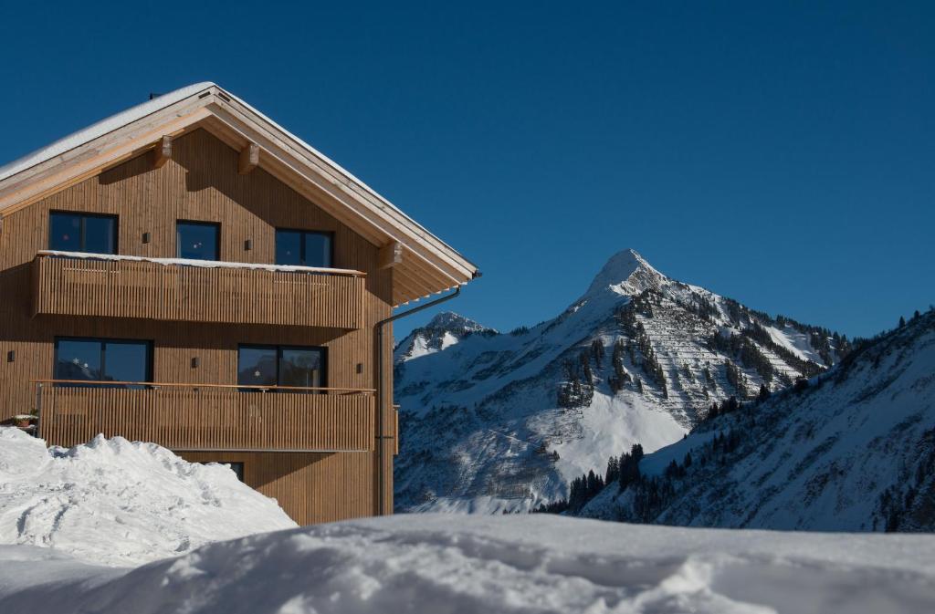 un edificio nella neve di fronte a una montagna di Appartements Berg 170 a Damuls