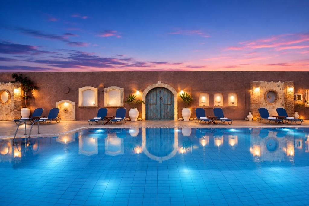 a large swimming pool with chairs and a building at Golden Bay Apartments-Garden Haven in Malia