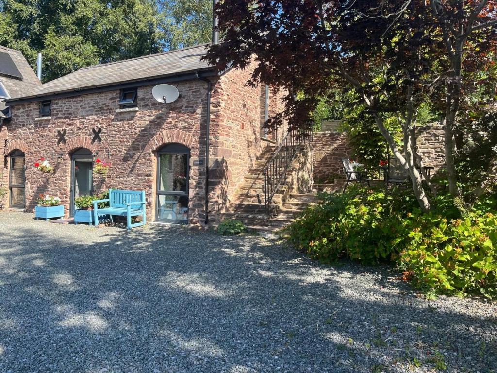 a brick building with blue benches in front of it at Ty Bach Coch in Scethrog