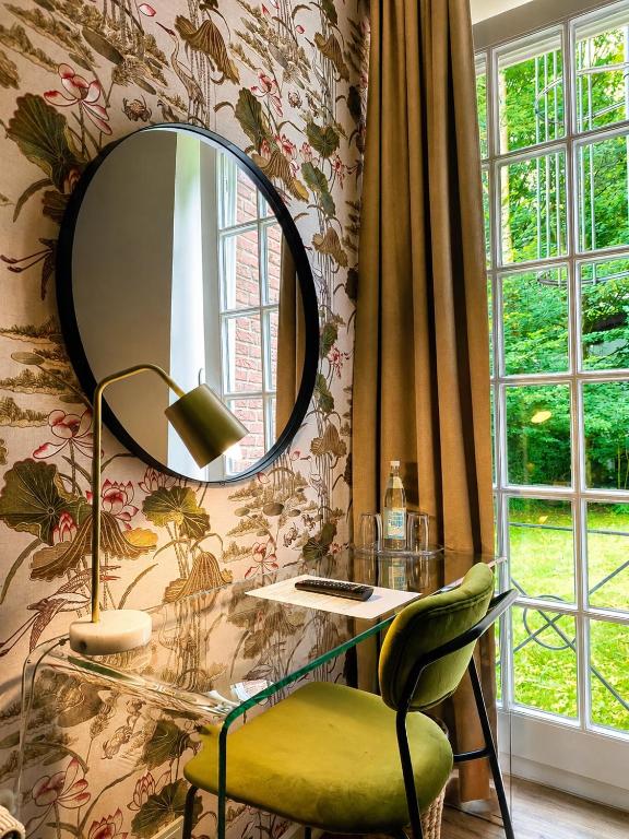 a mirror on a wall with a desk and a chair at Les Jardins Blankenese in Hamburg