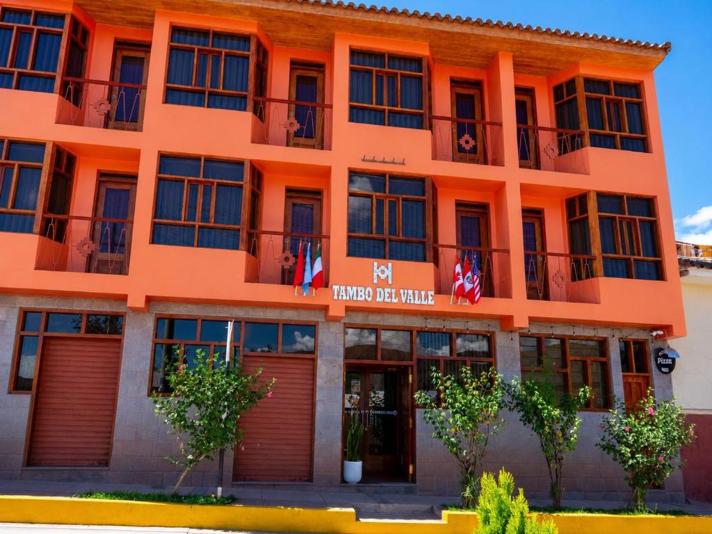 an orange building with flags in front of it at Hotel Tambo del Valle in Urubamba
