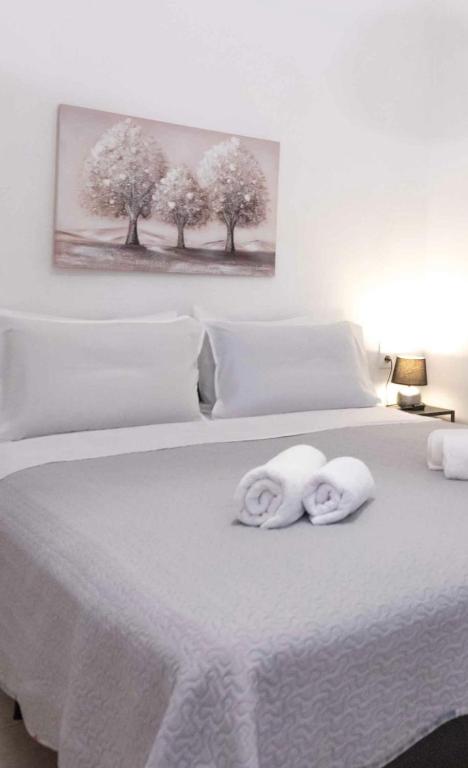 a white bed with two towels on top of it at Angie's House Volos in Volos