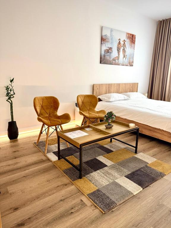 a bedroom with a bed and two chairs and a coffee table at Contemporary Studio with Balcony - New Building in Bucharest