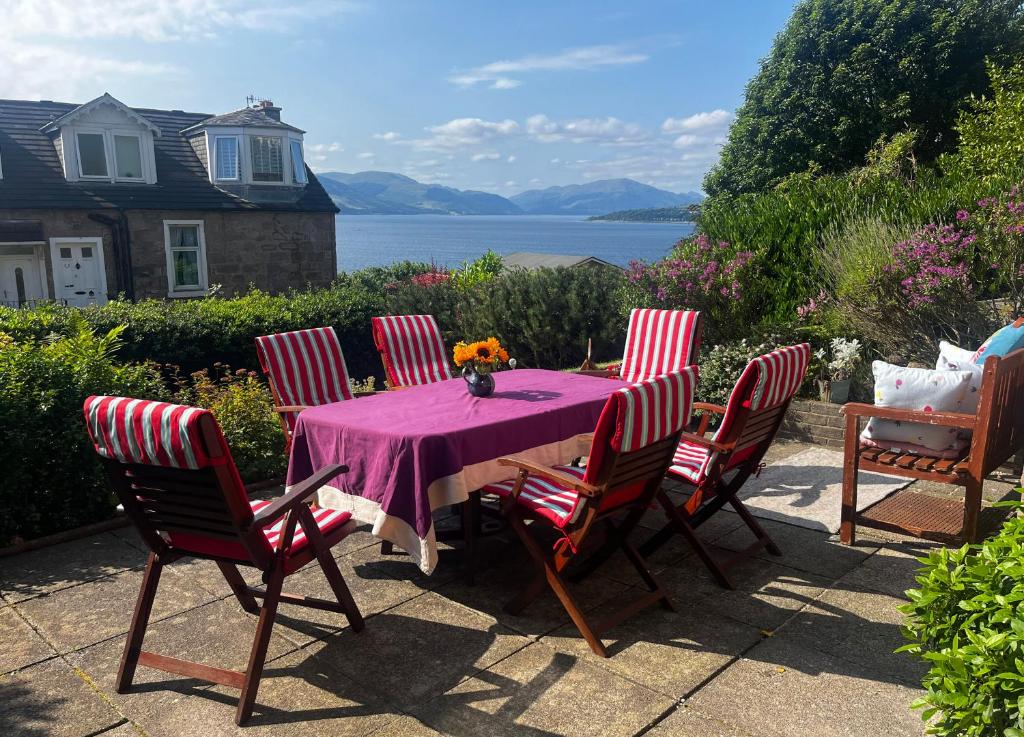 a table with four chairs and a purple table cloth at Lochview at 33a in Gourock