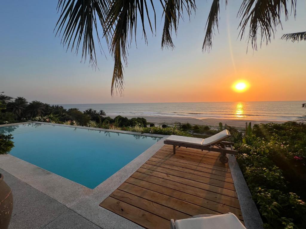 a swimming pool with a view of the ocean at sunset at Bed and breakfast ALDIANA in Cap Skirring
