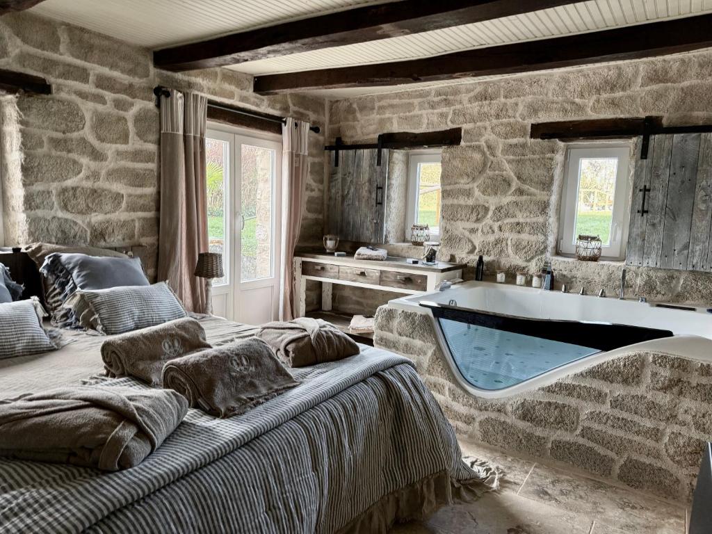 a bedroom with a bath tub in a stone wall at Le Petit Refuge - La Petite Longère in Rahon