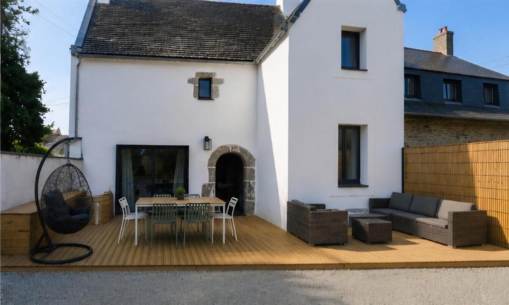 a white house with a deck with a table and chairs at "Chez mémé" in Locquirec