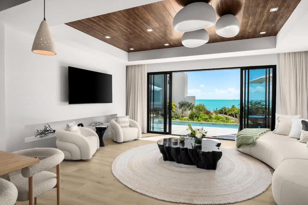a living room with white furniture and a large window at Villa Angelina in Leeward