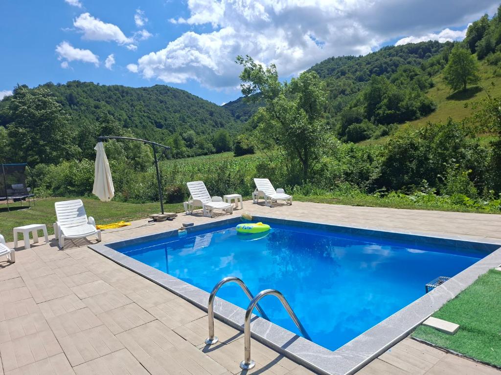 a swimming pool with chairs and a mountain in the background at Vikendica Mandic in Gornji Volari