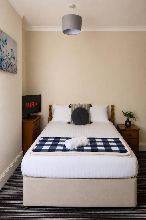 a bedroom with a bed with a blue and white checkered blanket at 52 - room 3 - smart TV in Swansea