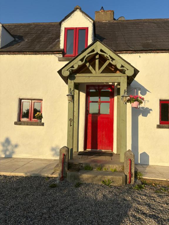 a house with a red door and red windows at THE FARMHOUSE Room 1 in Balcunnin