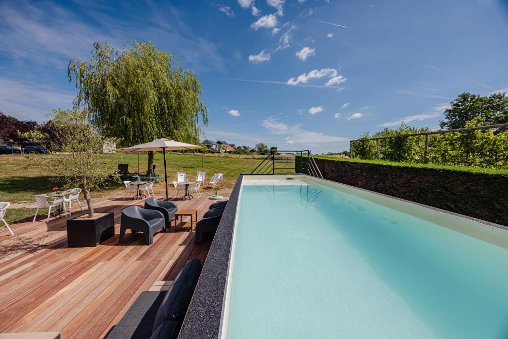a swimming pool with chairs and a table and an umbrella at Hotel & Restaurant Maison Pal'Ange in Durbuy