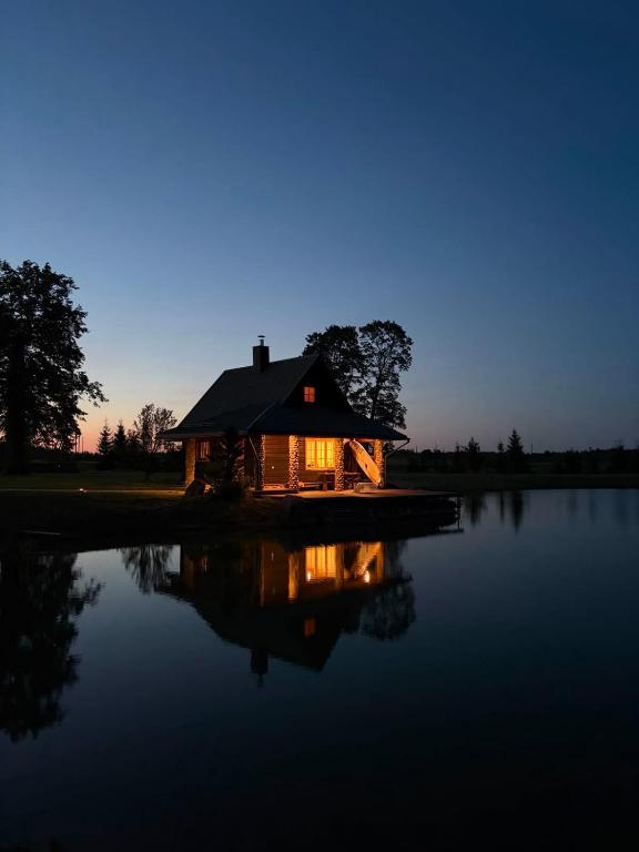 a house sitting on top of a lake at night at Milžinai Retreat in Zarasai