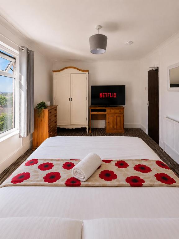 a bedroom with a white bed with red flowers on it at 52 - room 4 - city view in Swansea