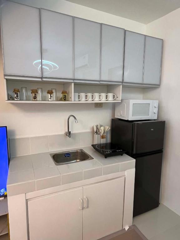 a small kitchen with a sink and a black refrigerator at Zensean Haven in General Santos