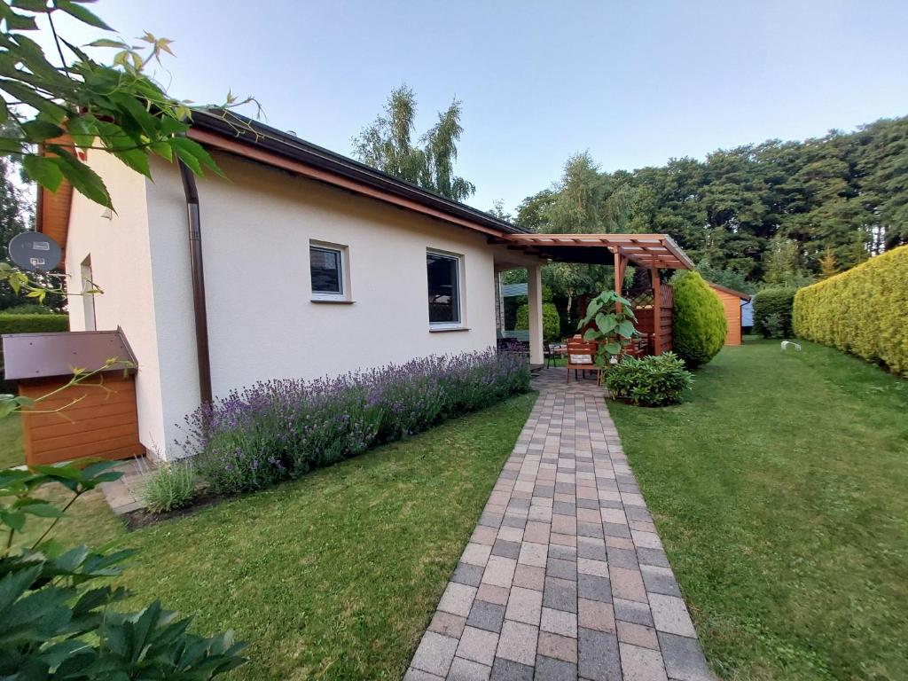 a garden with a house and a brick walkway at domek Lawendowy na wiejskiej in Lubiatowo