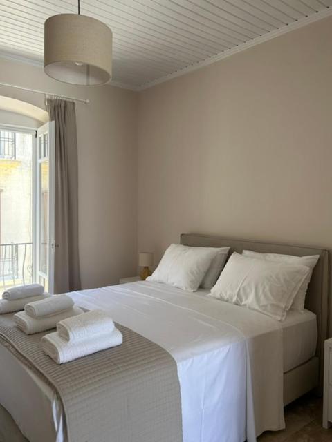 a white bedroom with a large bed with towels on it at Arco Boutique Apartments in Paralio Astros