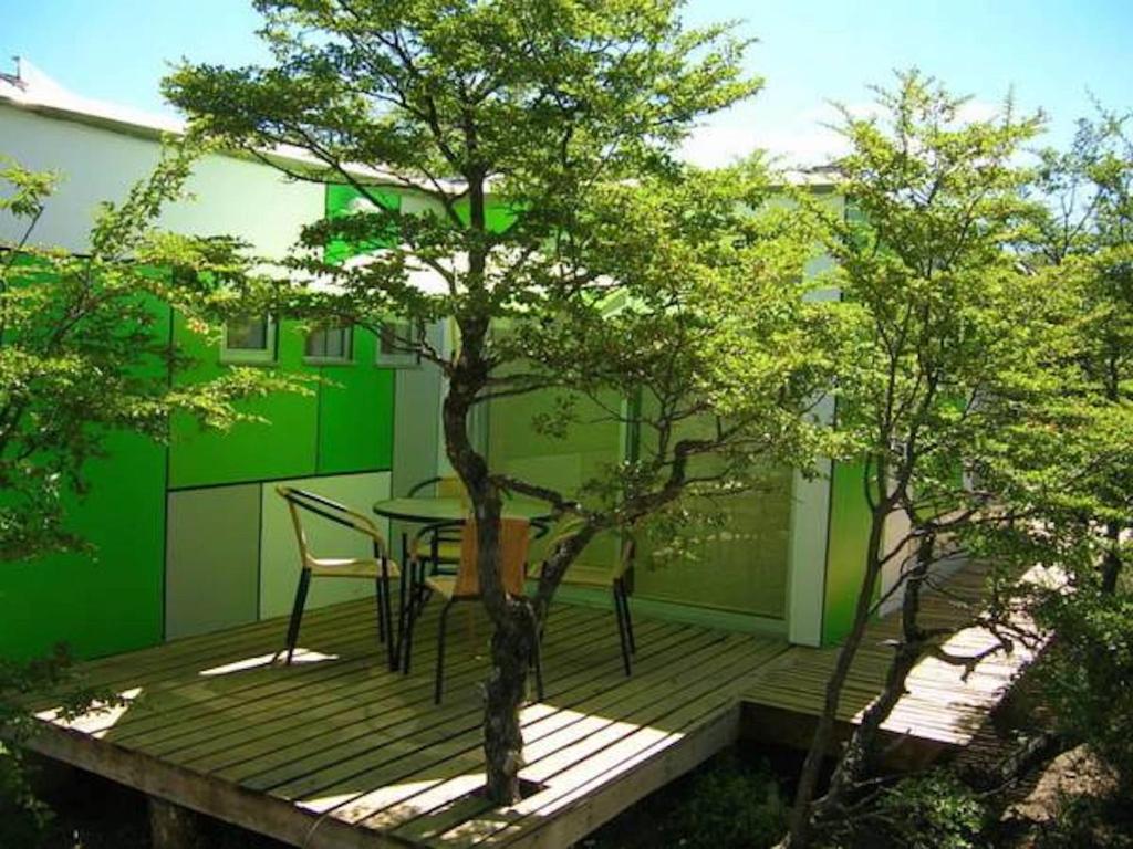 una mesa y sillas en una terraza de madera con un árbol en Cabañas Ecobox Andino, en Las Trancas