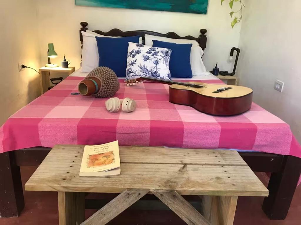 a bed with a guitar and a table with a book at Canto Alegre Pernambuco in Goiana