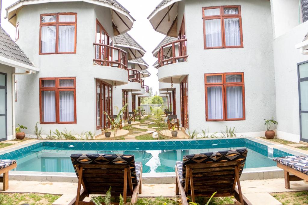an apartment with a swimming pool in front of two buildings at Olarashii River Lodge in Arusha