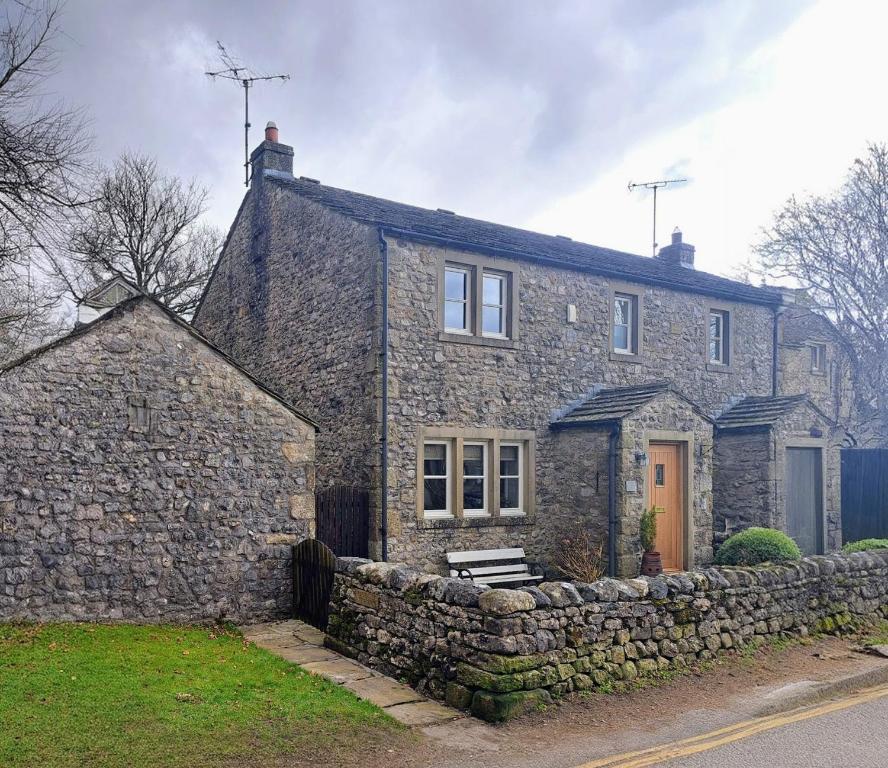an old stone house with a stone wall at Woodside Cottage in Skipton