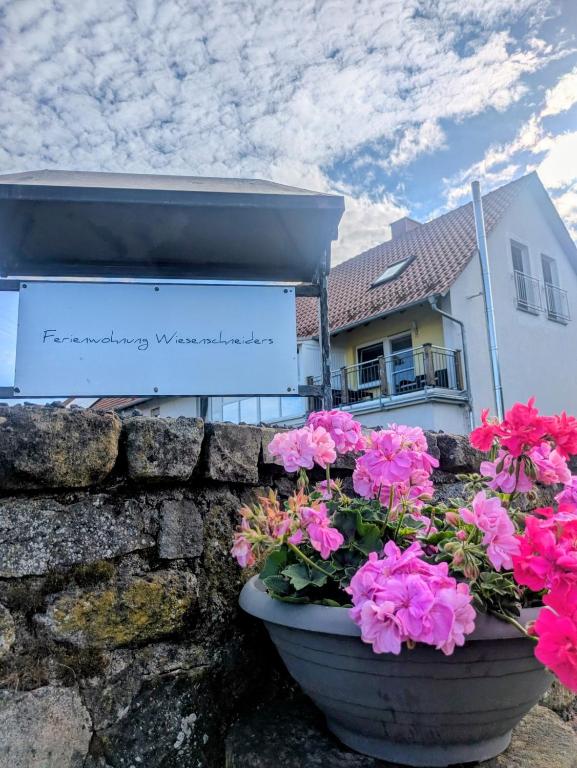 a stone retaining wall with flowers in front of a building at Ferienwohnung Wiesenschneiders in Freiensteinau