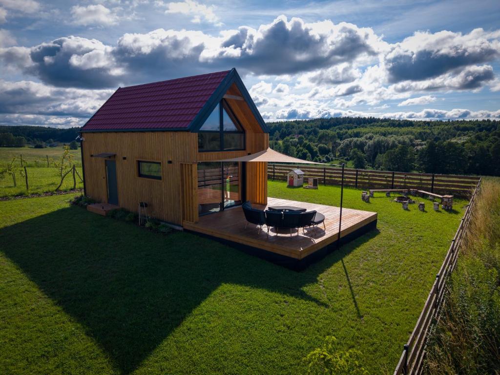 a house with a red roof on a green field at Stodoła Nad Dadajem in Kojtryny