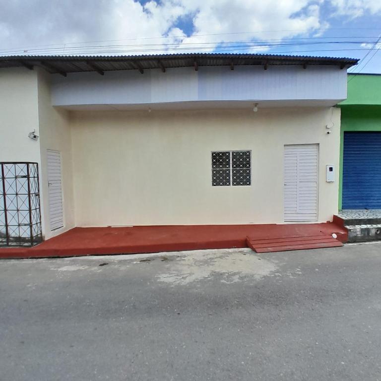 a white house with a red door and a gate at Pousada Amiga in Parintins