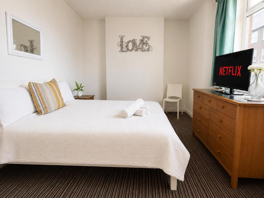 a bedroom with a bed with a television and a dresser at 52 - room 1 - city views in Swansea