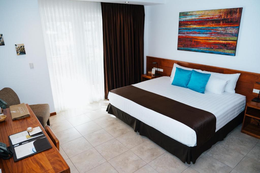 a bedroom with a large bed with blue pillows at Hotel Cucuve in Puerto Ayora