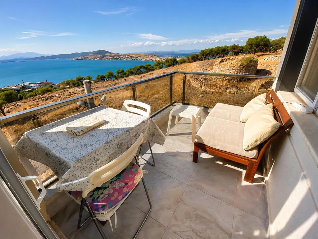 a table and chairs on a balcony with a view of the ocean at Ada Hill Ayvalık in Ayvalık