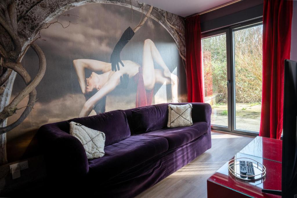 a living room with a purple couch and a large painting at L'Avant-Première Chic 40m2 with Parking in Évreux