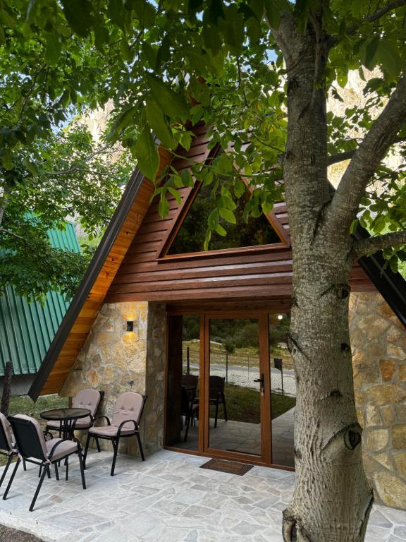 a house with glass doors and chairs next to a tree at Villa Komarnica Hideaway in Šavnik