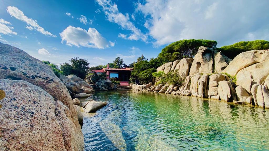 a river with rocks and a house in the background at Villa Mica in La Maddalena
