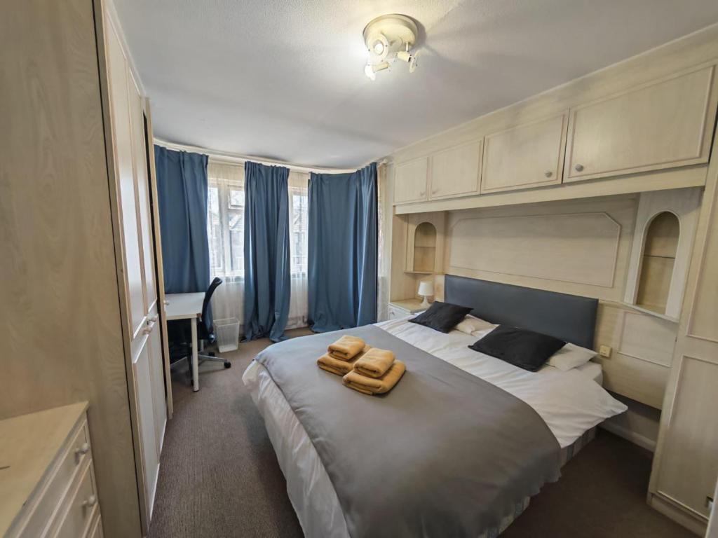 a bedroom with a large bed with blue curtains at Standard Double Room with Shared Bathroom in London