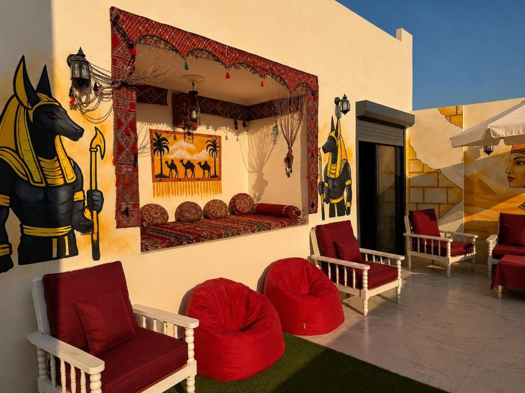 a room with red chairs and a horse picture on the wall at Pyramids View Rooftop Apartment in Ghaţāţī