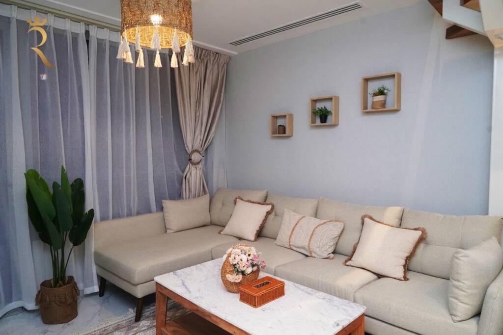 a living room with a couch and a table at Elegant 2BR Jade Serenity - Masdar City Retreat in Al Qurayyah