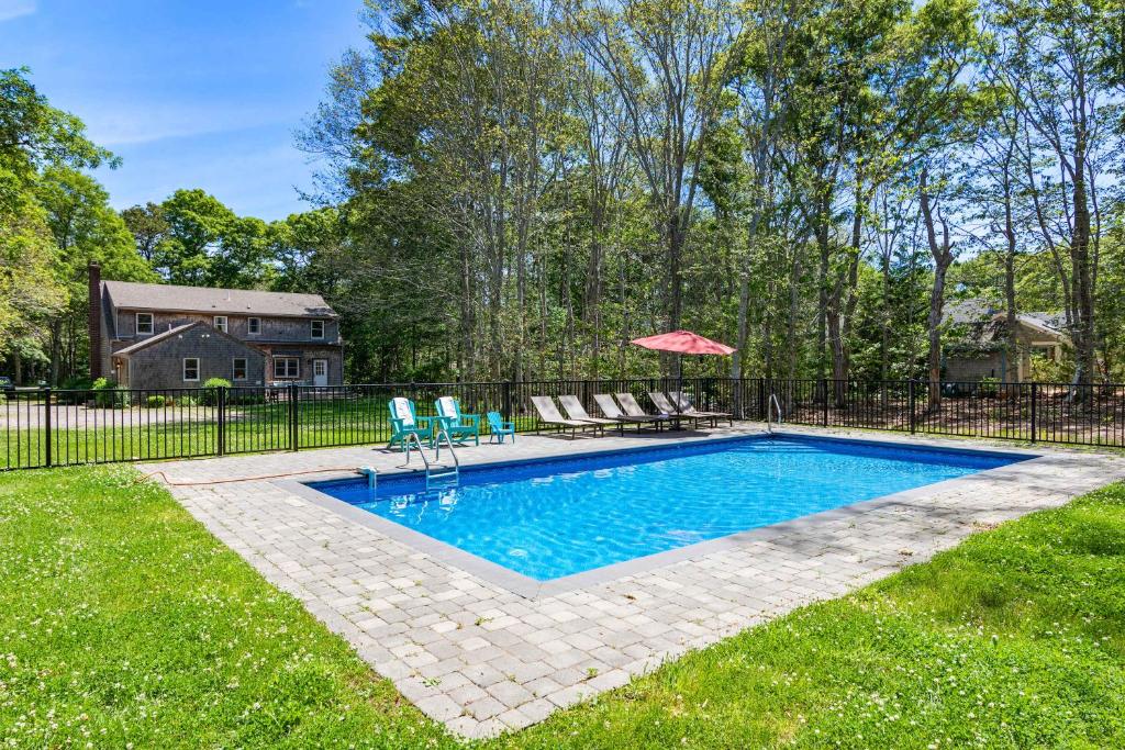a swimming pool in a yard with two chairs and an umbrella at Spacious Home with Private In-Ground Pool in Brewster