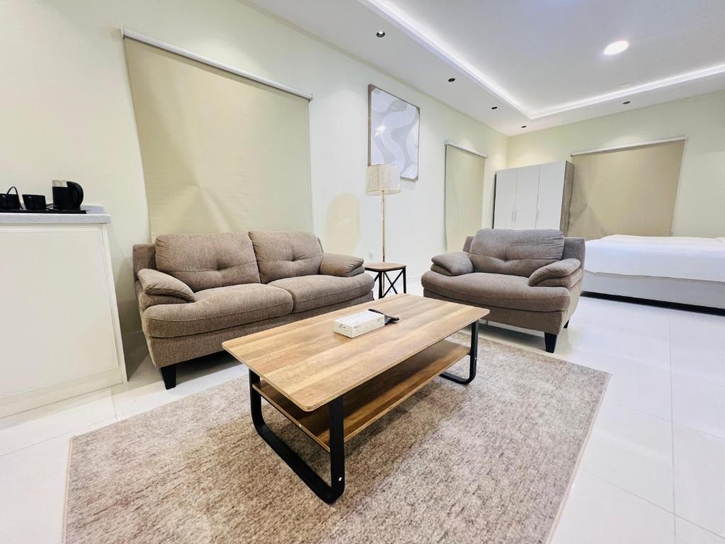 a living room with two couches and a coffee table at فـيليج سـانـسـت Village Sunset in Al Namas