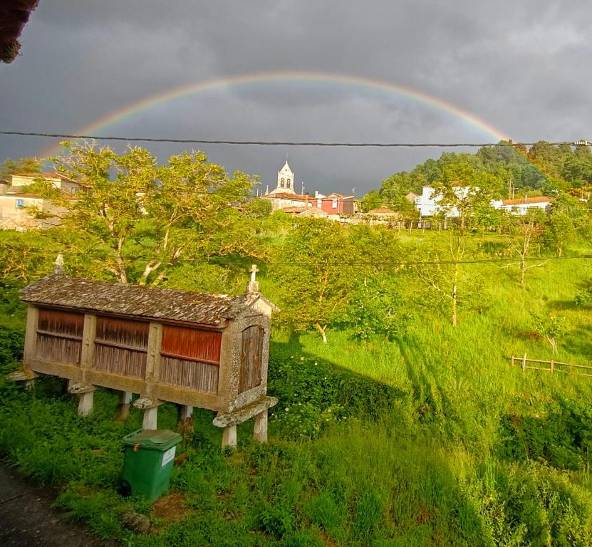 a rainbow over a small house in a field at A Casiña do Río in Celanova