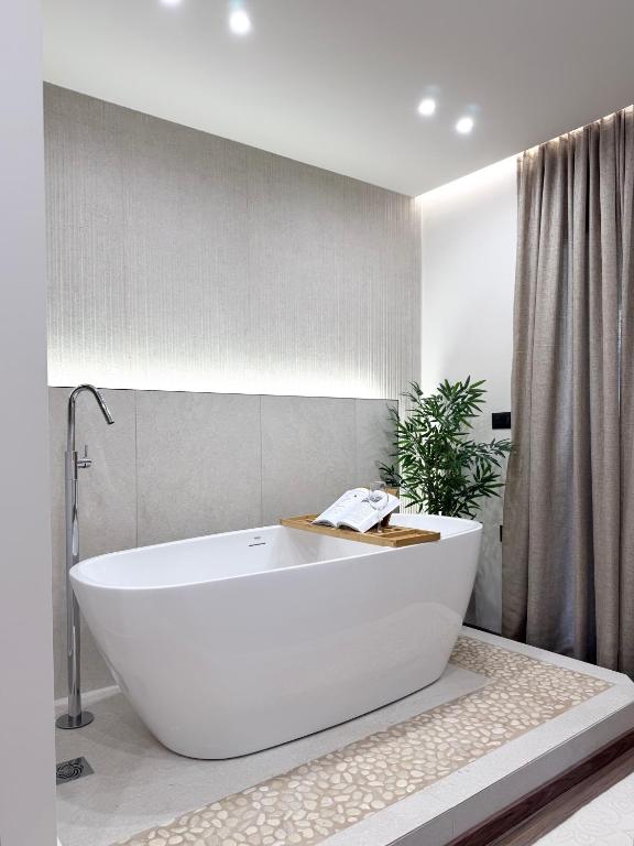 a white bath tub in a bathroom with a plant at EROS & PATHOS Suites in Kremasti