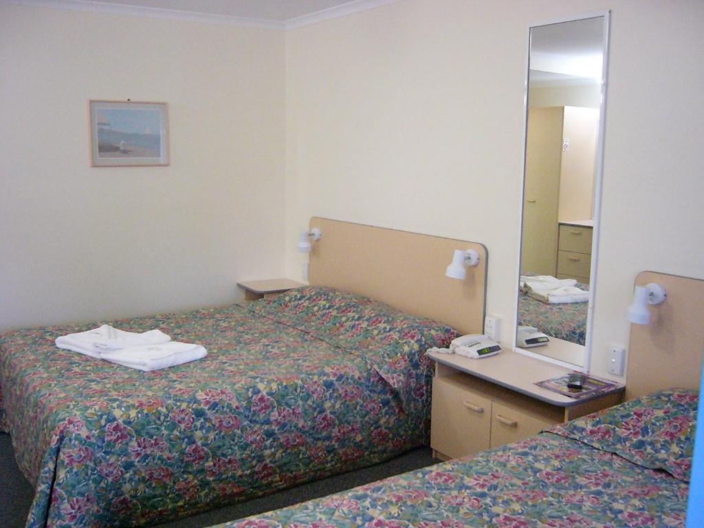 a hotel room with two beds and a mirror at Mid Coast Motor Inn in Macksville