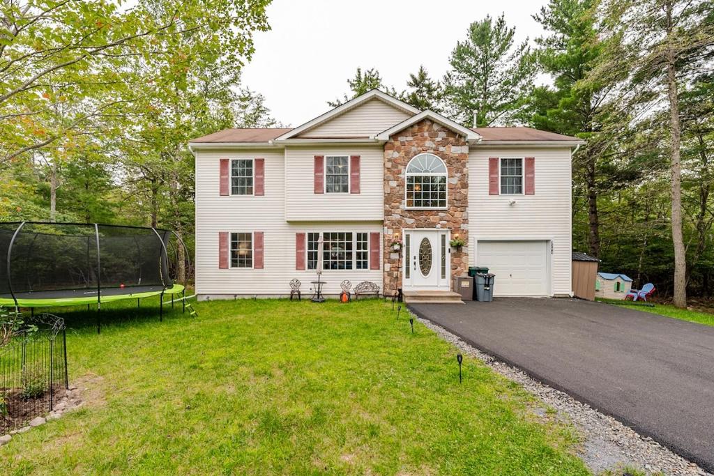 a house with a driveway in front of a yard at Golden Deer Lodge Hot Tub Sauna Sleeps 12 in Tobyhanna