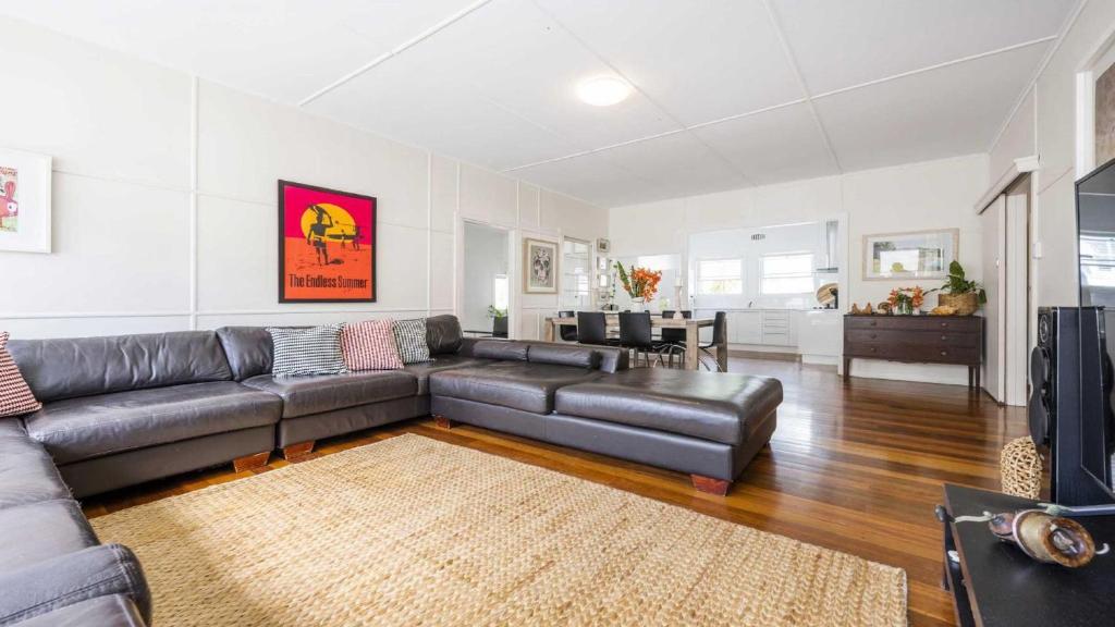 a living room with a leather couch and a table at Leonards Beachshack - Lifestyle Yamba in Yamba
